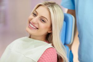Smiling young woman seated at orthodontics appointment | Life after braces