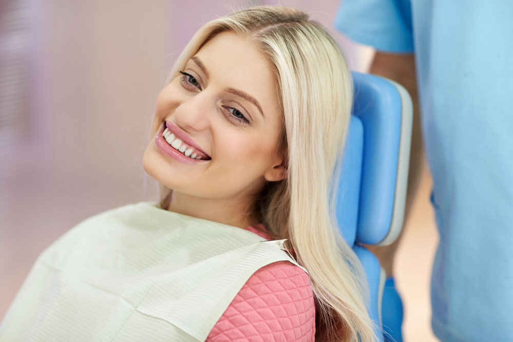 Smiling young woman seated at orthodontics appointment | Life after braces